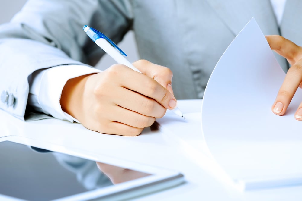 Closeup of a businesswoman signing documents to suggest Meta's regulatory fines and GDPR compliance